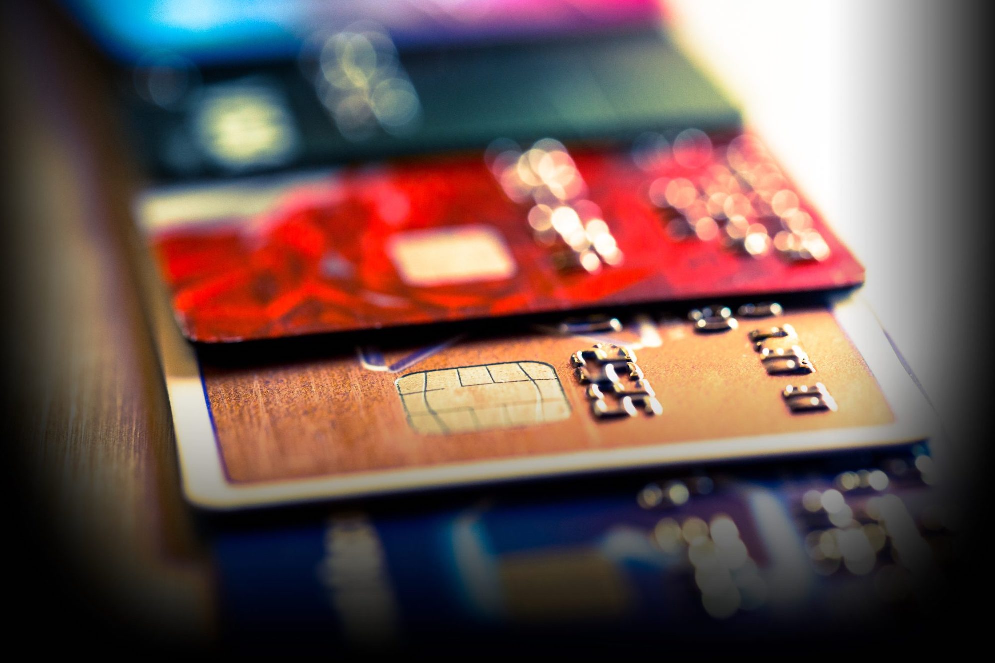 Close up macro color image depicting an abstract view of a collection of debit and credit cards and numeric digits.